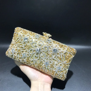 Detailed view of hollow floral pattern on a gold evening clutch with sparkling rhinestones