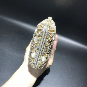 Close-up of gold镂空 evening bag with sparkling crystals and oval opal stones in hand