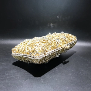 Macro shot of gold hollow metal frame and sparkling inlaid crystals on evening clutch