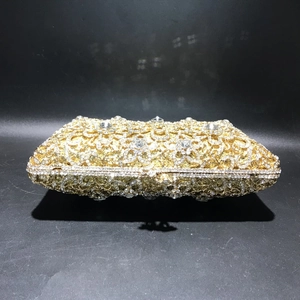 Close-up of golden hollow evening clutch bag with sparkling floral rhinestone details