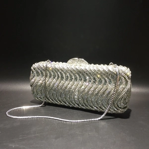 Detailed close-up of silver evening clutch featuring wave pattern rhinestones and metal chain