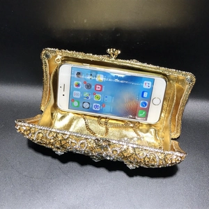 Detail showing internal capacity of gold rhinestone evening bag holding a smartphone