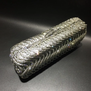 Detail of silver evening clutch bag featuring S-shaped wavy rhinestone patterns and metal frame