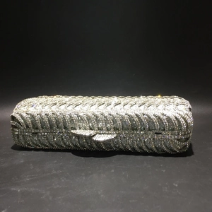 Close-up of silver evening clutch featuring intricate rhinestone feather patterns