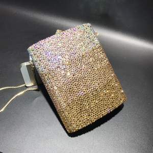 Macro detail of gradient crystal evening clutch with gold chain beside a smartphone