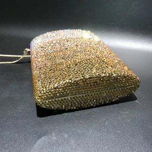 Close-up of golden crystal evening clutch featuring a gradient rhinestone metal frame