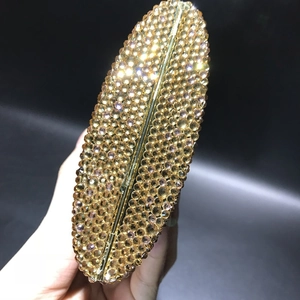 Detailed close-up showing hand-set amber crystals on a luxury golden metal clutch bag