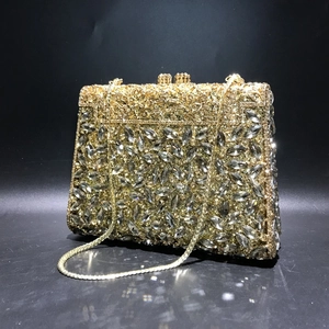 Close-up of gold evening clutch with sparkling marquise rhinestones and hollow metal detail