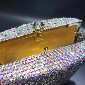 Macro detail of luxury evening clutch showing iridescent crystals and gold metal clasp