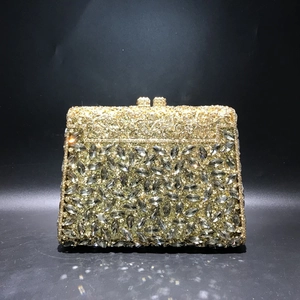 Macro detail of luxury golden evening bag with grey teardrop rhinestones and hollow metalwork