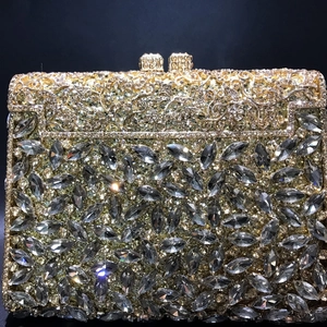 Close-up of golden hollow metal evening bag with marquise grey rhinestones and dual square clasp