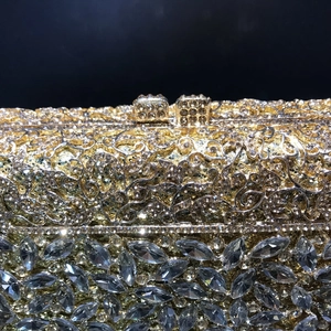 Macro shot of luxury gold evening clutch with hollow metal patterns and marquise rhinestones