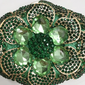 Detailed macro of emerald green rhinestones and heart-shaped crystals on luxury clutch