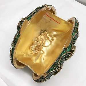 Detail of green rhinestone evening clutch showing gold interior and chain strap