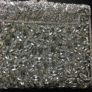 Macro detail of silver evening clutch with crystal inlay and hollow floral metalwork