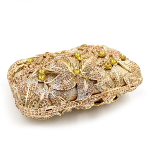 Detail of luxury gold evening clutch with hollow metal flowers and crystal inlay