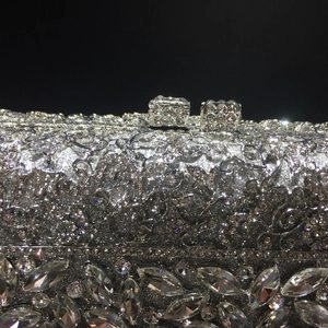 Detail of silver evening clutch with metal cutout pattern and crystal latch close-up