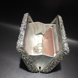 Detail of silver rhinestone evening clutch interior with chain and smartphone for scale