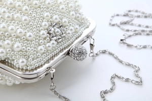 Detailed side view of large pearl evening clutch bag with rhinestone floral accents