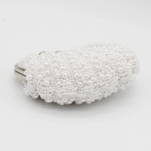 Close-up of elegant pearl evening clutch bag with various white pearls and silver metal frame