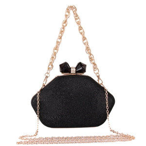 Detail of black glitter evening bag featuring a sparkling crystal bow clasp and gold chain