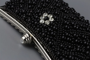 Makro-Detail der schwarzen Perlen-Abendtasche mit glitzernder Strassblume und Silberverschluss