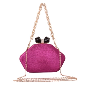 Close-up of fuchsia glitter evening clutch bag with black bow clasp and gold chain
