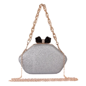 Detail of silver glitter evening bag featuring a rhinestone bow and gold chain strap