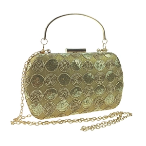 Close-up of golden sequin evening bag with spiral patterns and metallic handle