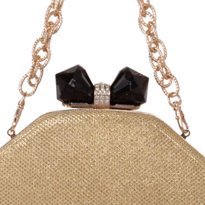 Detail of gold sequin clutch bag with black gem bow clasp and metal chain strap
