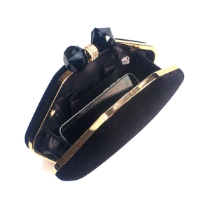 Detail of black velvet evening clutch with golden frame and jeweled bow clasp