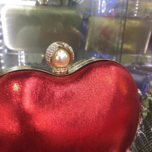 Vista macro di una borsa da sera rossa a cuore con chiusura in perle e strass