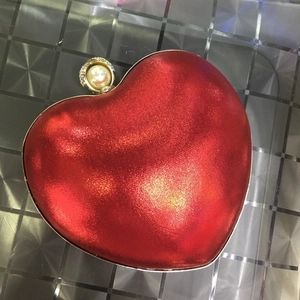 Dettaglio della pochette rossa a forma di cuore con chiusura a perla e strass brillanti