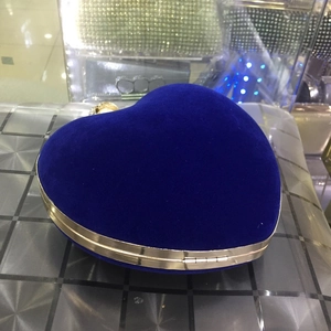 Détail d'un sac de soirée coeur en velours bleu avec cadre en métal doré et fermoir
