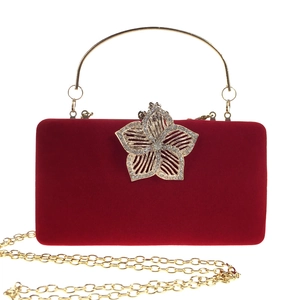 Détail de pochette de soirée en velours rouge avec fermoir fleur dorée et strass