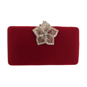 Détail d'une pochette de soirée en velours rouge avec fermoir fleur dorée et diamants