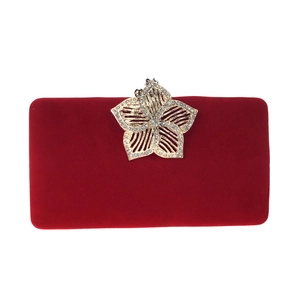 Détail du fermoir fleuri orné de cristaux sur une pochette de soirée en velours rouge