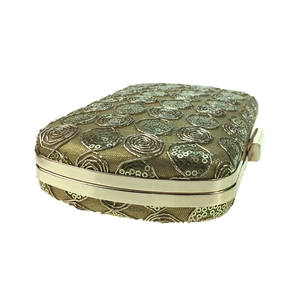 Close-up of champagne gold evening clutch with spiral sequins and metal clasp