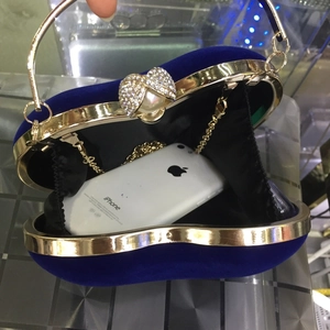 Détail de la pochette coeur en velours ouverte avec chaîne et téléphone pour échelle
