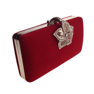 Détail de la pochette en velours rouge avec fermoir floral doré serti de strass