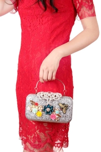 Dettaglio borsa da sera con paillettes argento, fiori 3D, perle e decoro a ape