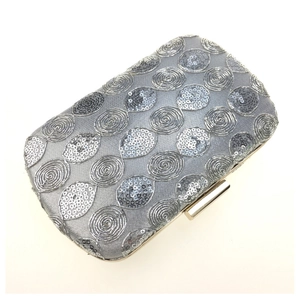 Detailed view of silver sequin swirl pattern on hard shell evening clutch bag