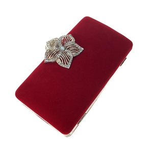 Détail macro de la pochette de soirée en velours rouge avec fleur argentée sertie de strass