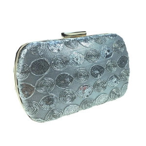 Macro detail of silver spiral sequins on a structured evening clutch with gold clasp