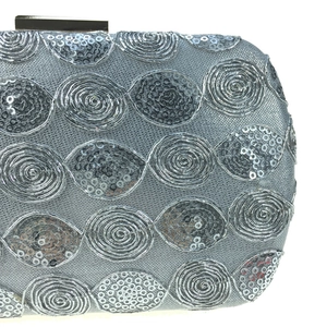 Close-up of silver sequin evening bag with spiral wave patterns and metal clasp