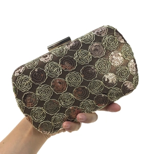 Macro detail of sequined floral embroidery on a golden evening clutch bag with push-lock