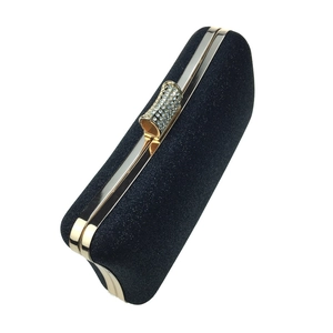 Close-up of black shimmer evening clutch with gold metal frame and rhinestone clasp