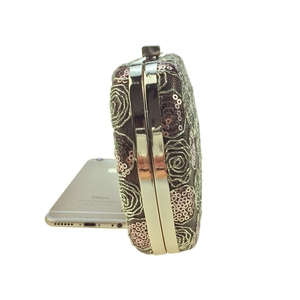 Side view of champagne sequin evening clutch with gold metal frame and snap closure