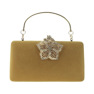 Détail de pochette de soirée en velours avec fleur dorée ajourée et cristaux