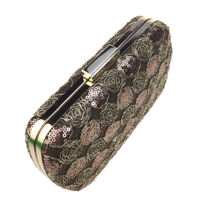 Macro shot of rose embroidery and shimmering sequins on a luxury square evening clutch bag